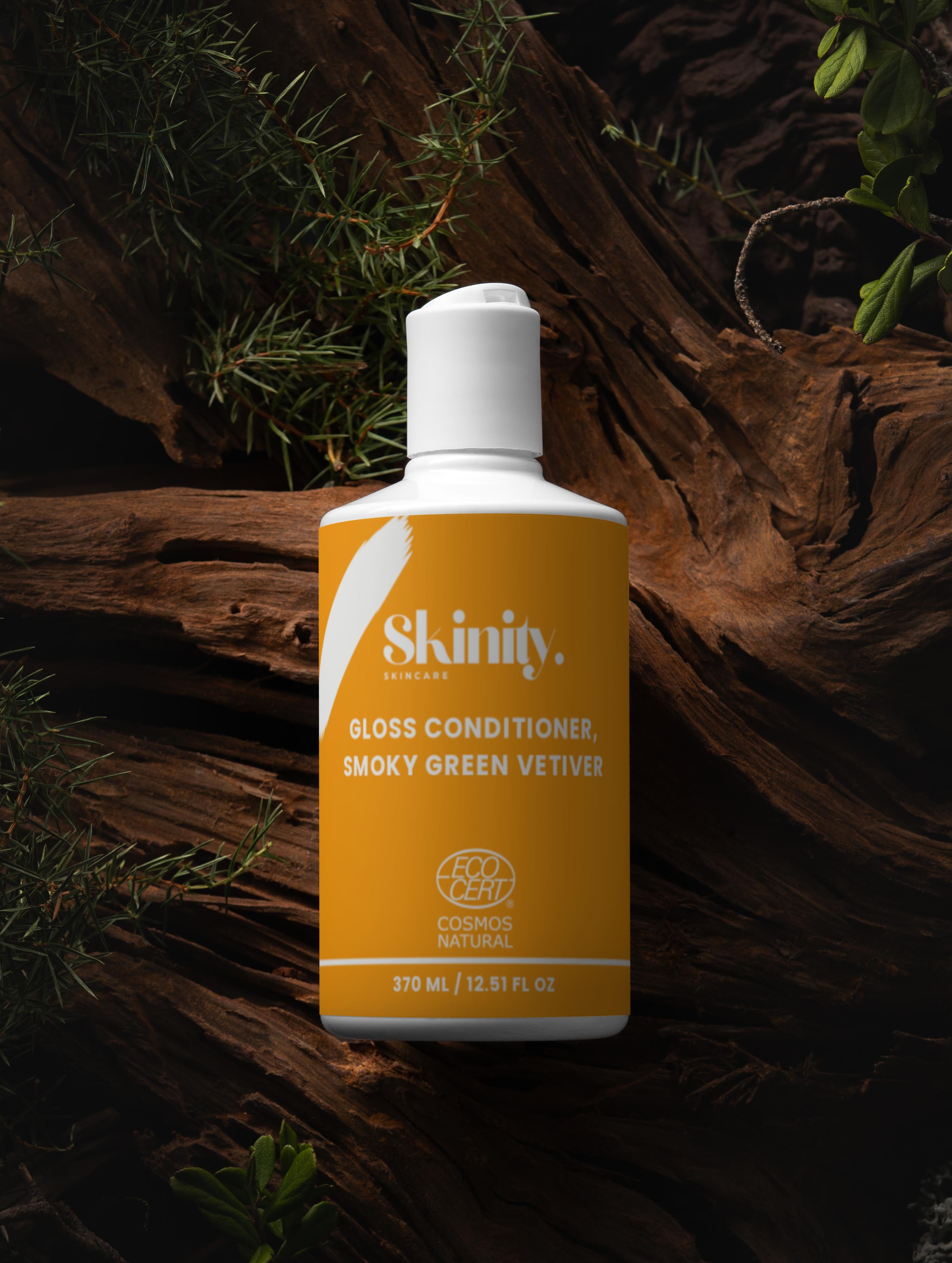 Gloss Conditioner Smoky Green Vetiver bottle on a natural wood background, highlighting its nourishing properties.