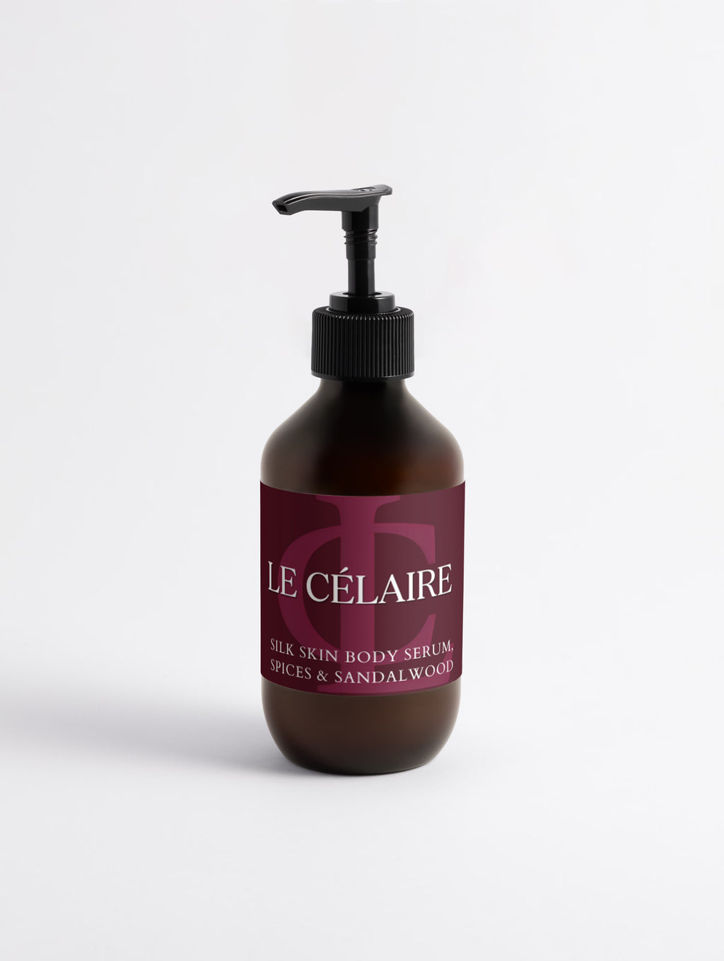 An amber glass pump bottle of Le Célaire Silk Skin Body Serum with a black pump and a dark burgundy label, set against a clean white background.