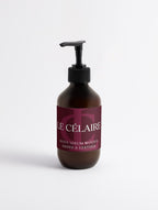 An amber glass pump bottle of Le Célaire Silk Skin Body Serum with a black pump and a dark burgundy label, set against a clean white background.