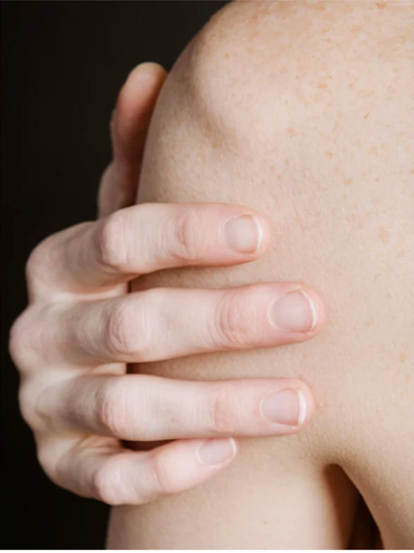 Close-up of a hand gently holding a shoulder with smooth skin, illustrating skincare care and touch.