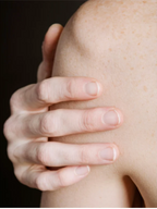 Close-up of a hand gently holding a shoulder with smooth skin, illustrating skincare care and touch.