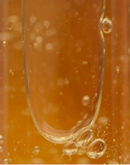 Close-up of bubbles in a golden liquid representing Moisturising Shampoo for all Hair types.