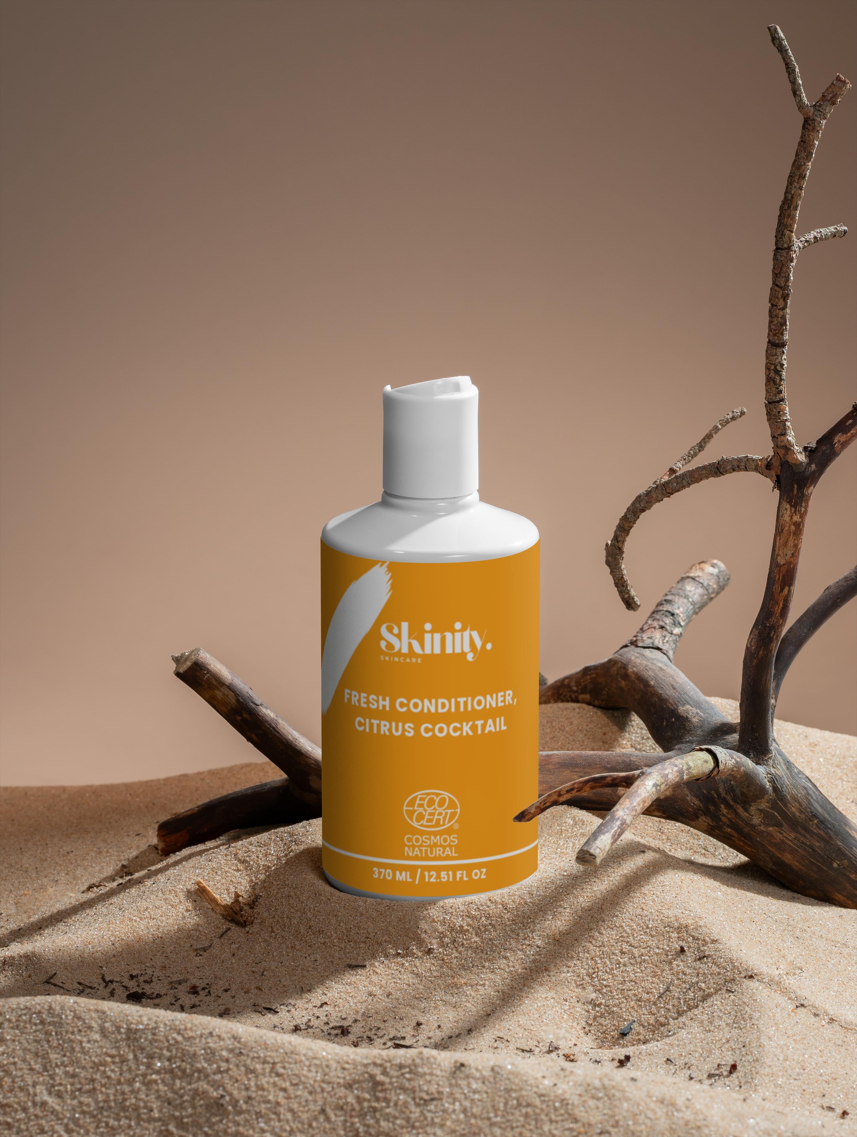 Fresh Conditioner Citrus Cocktail bottle on sand with driftwood background.