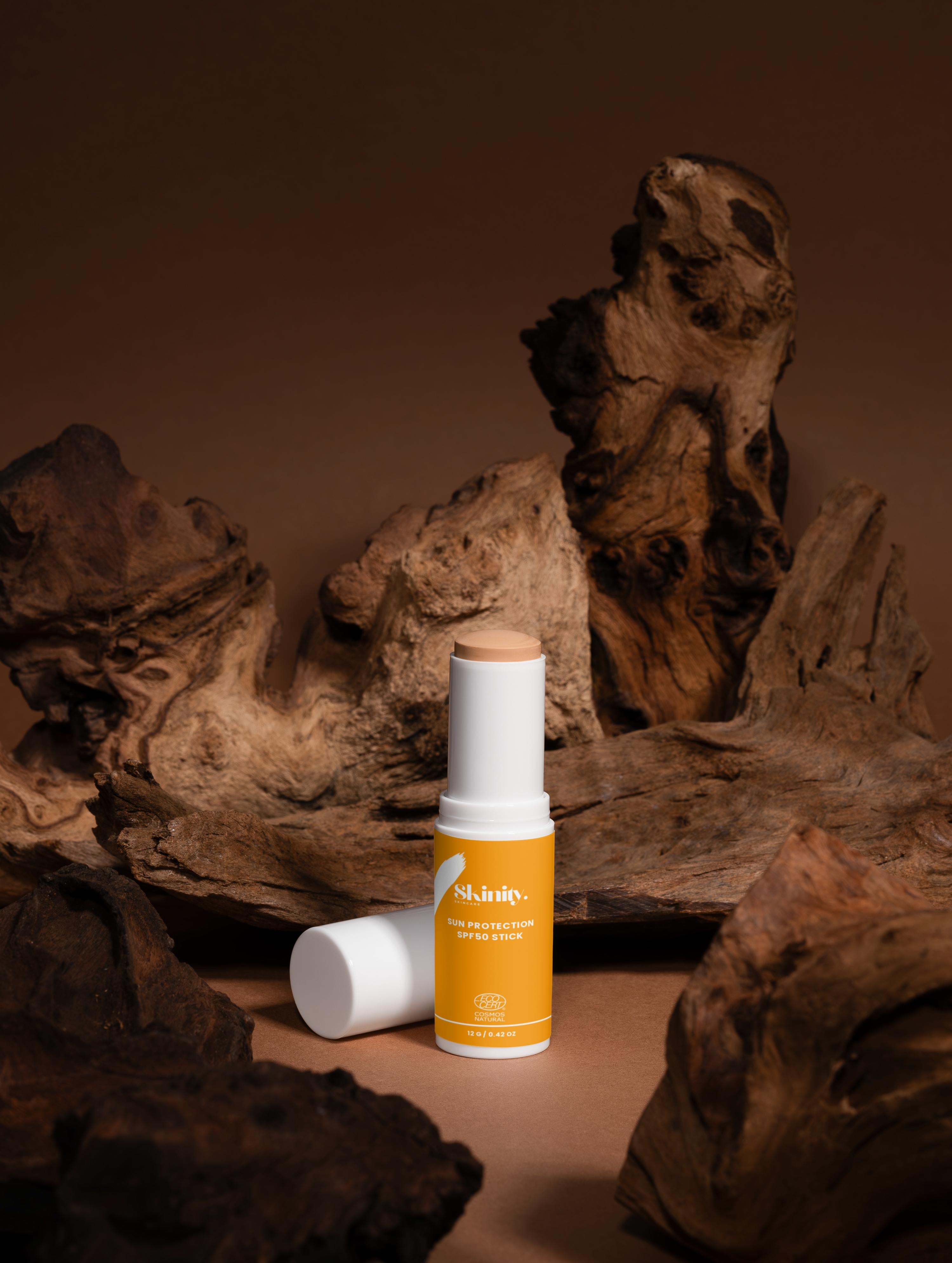 SPF 50 tinted sunscreen stick placed on textured wood background showcasing its sleek design.
