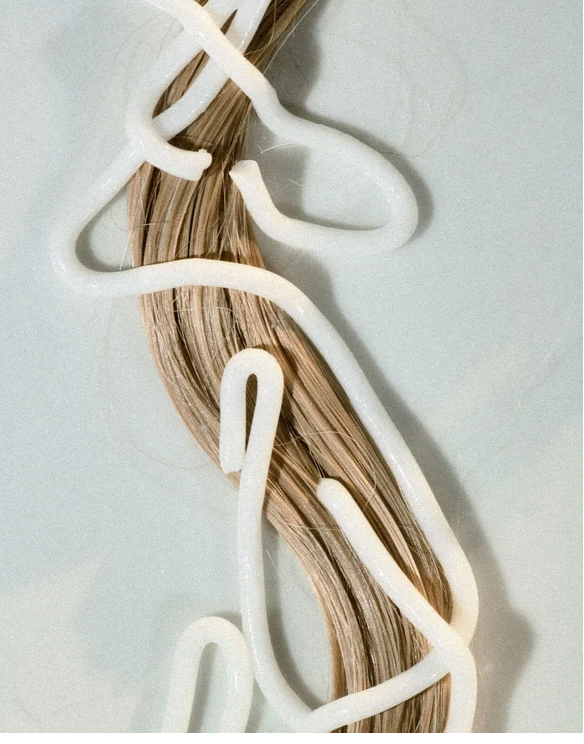Moisturising Conditioner for all Hair types on shiny hair strands against a pastel background.