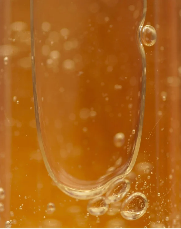 Close-up of bubbles in a golden liquid representing Moisturising Shampoo for all Hair types.