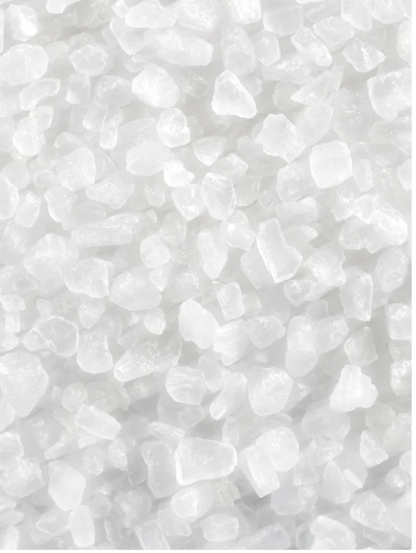 Close-up view of coarse, white mineral salt crystals with uneven shapes and sizes.