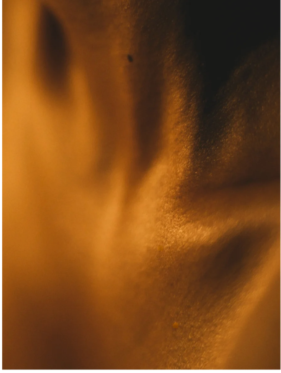 Close-up image of silky textured fabric with warm tones, highlighting the smooth and soft appearance of the material.