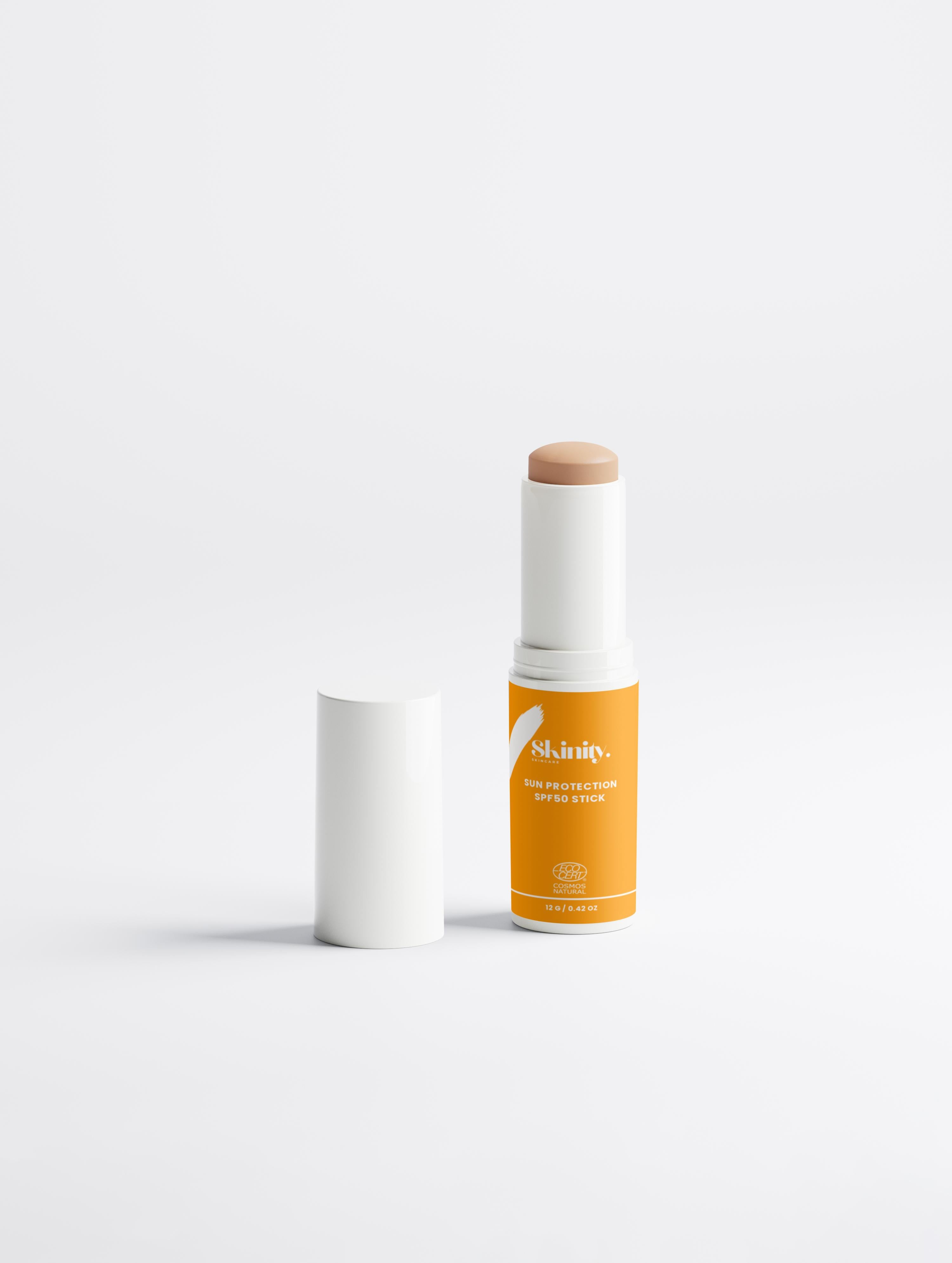 SPF 50 tinted sunscreen stick in a white and orange packaging on a plain background.