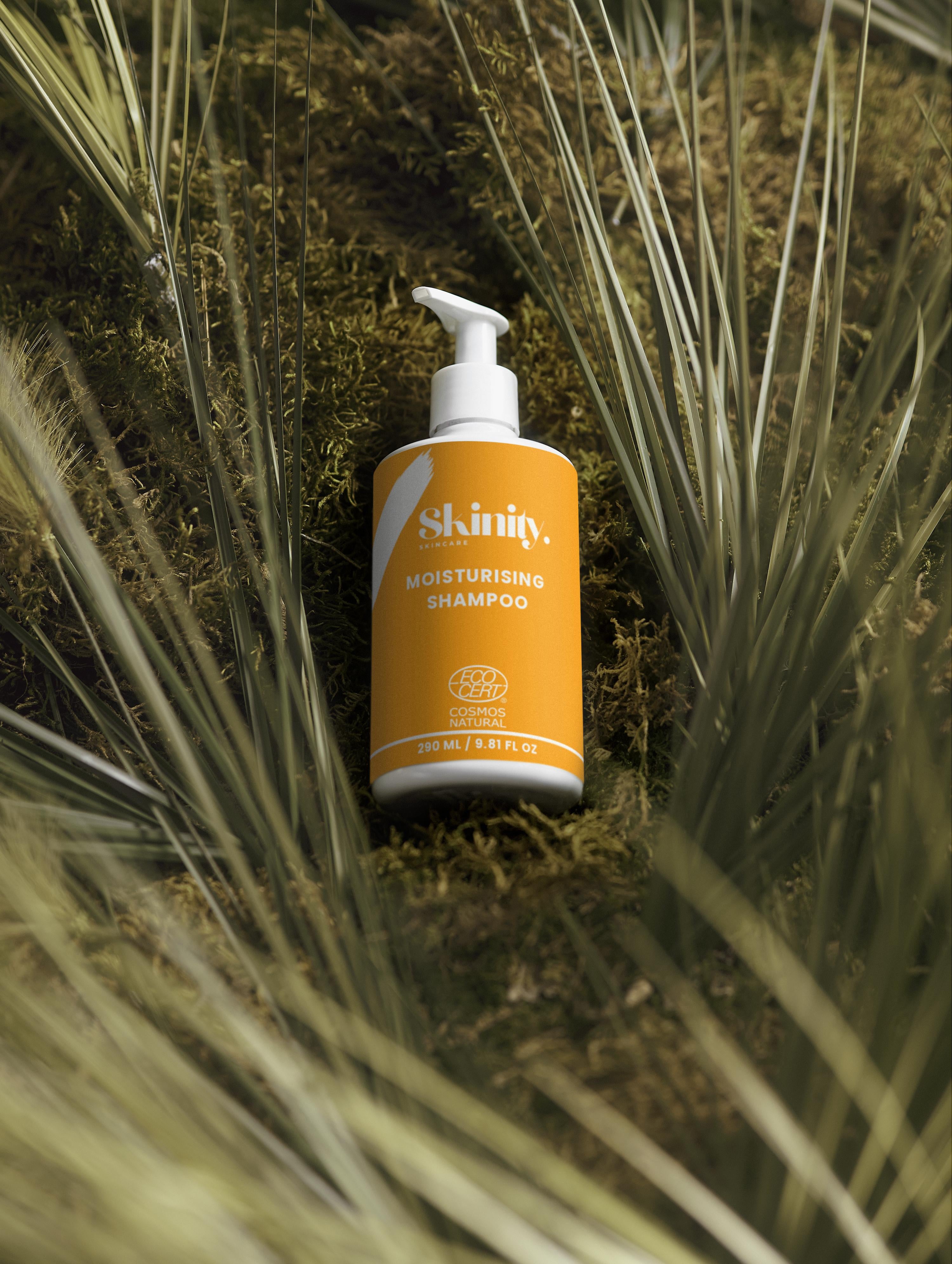 Moisturising Shampoo for all Hair types bottle displayed among green foliage.