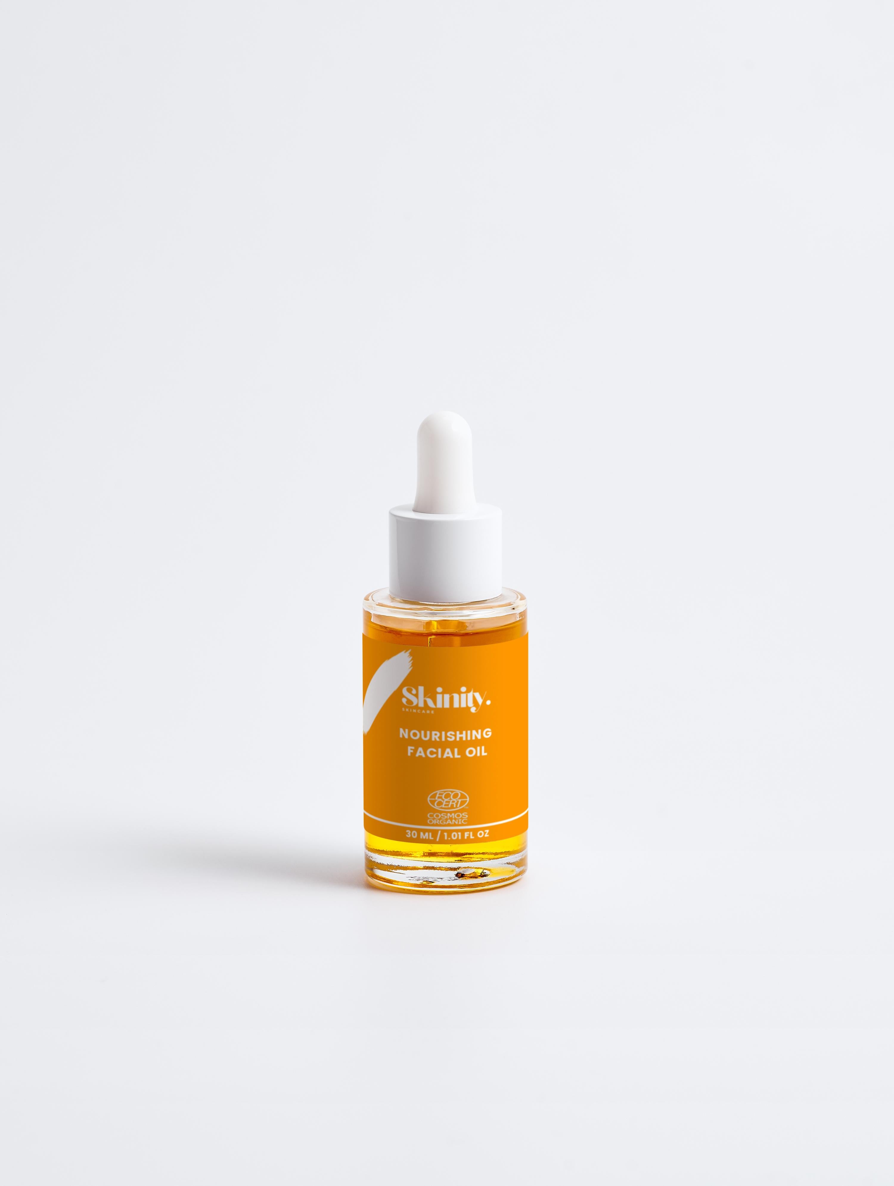 Nourishing Facial Oil For All Skin in a glass dropper bottle with orange oil and white label.