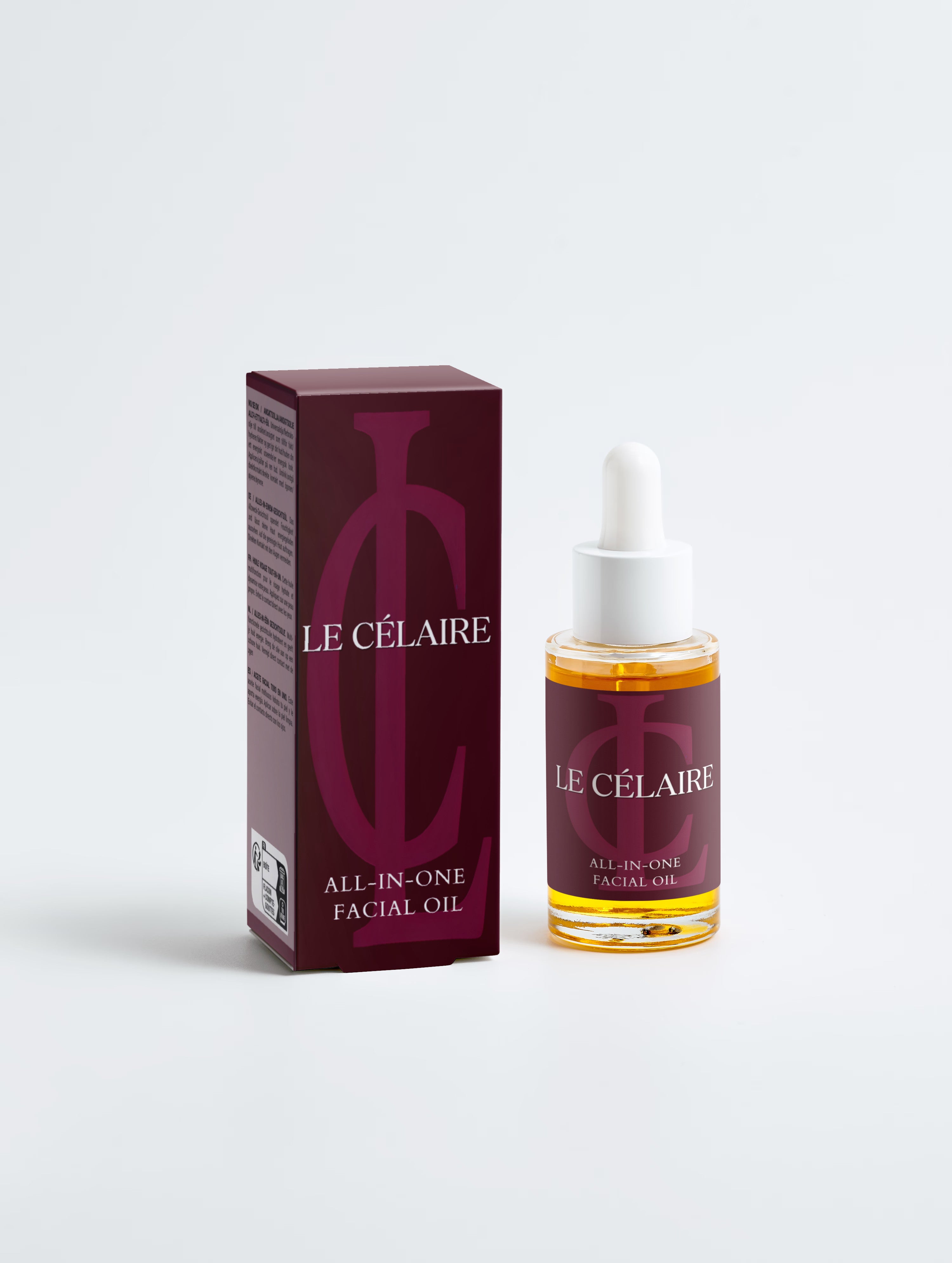 Le Célaire All-In-One Facial Oil shown with its dark burgundy packaging box and a clear glass dropper bottle containing golden oil, set against a clean white background.