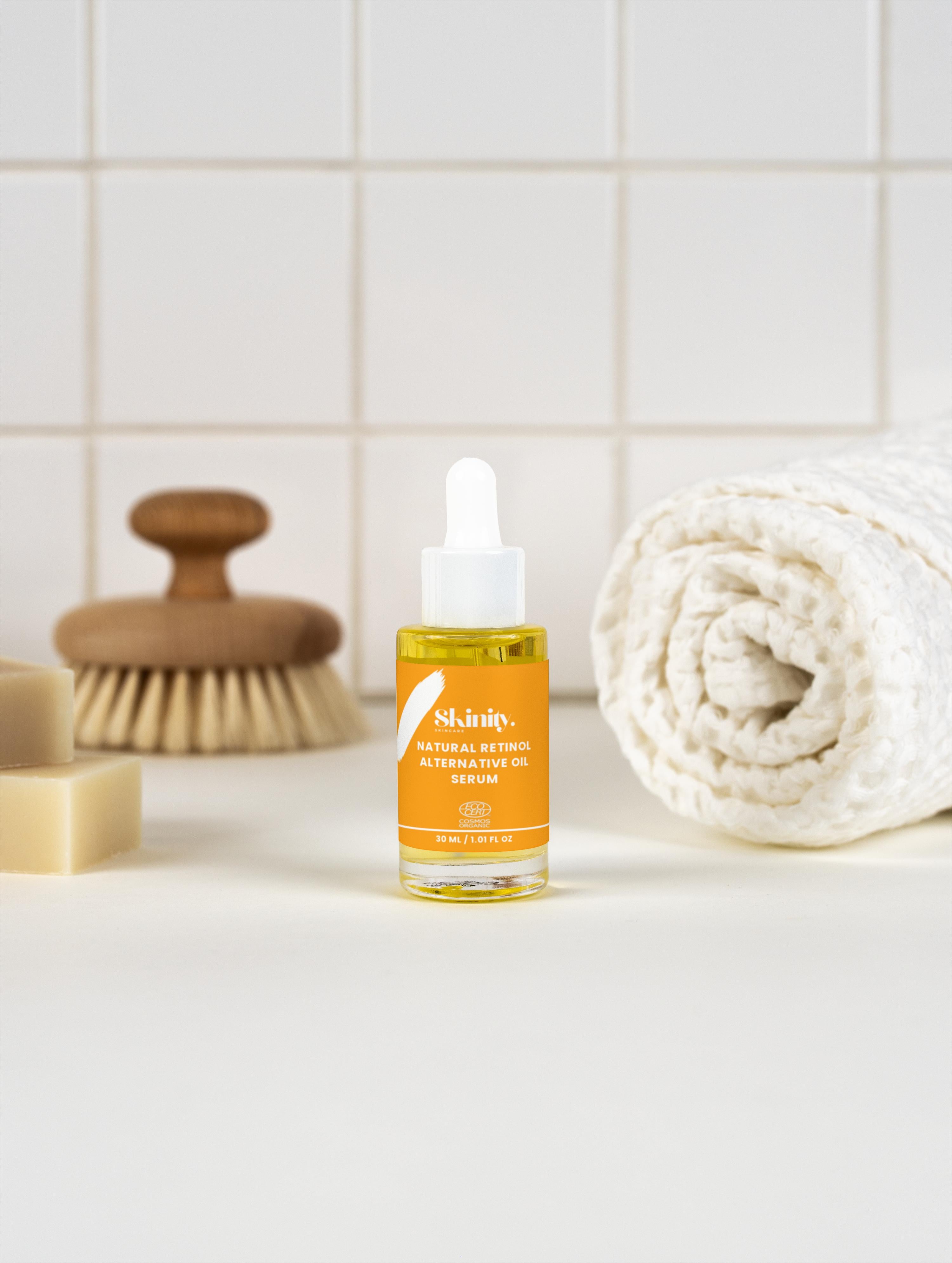 Natural Retinol Alternative Oil Serum in a glass dropper bottle next to a towel and wooden brush.
