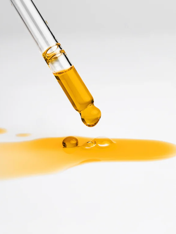 Droplet of All-In-One Facial Oil for all skin on a surface, showcasing its rich, nourishing formula.