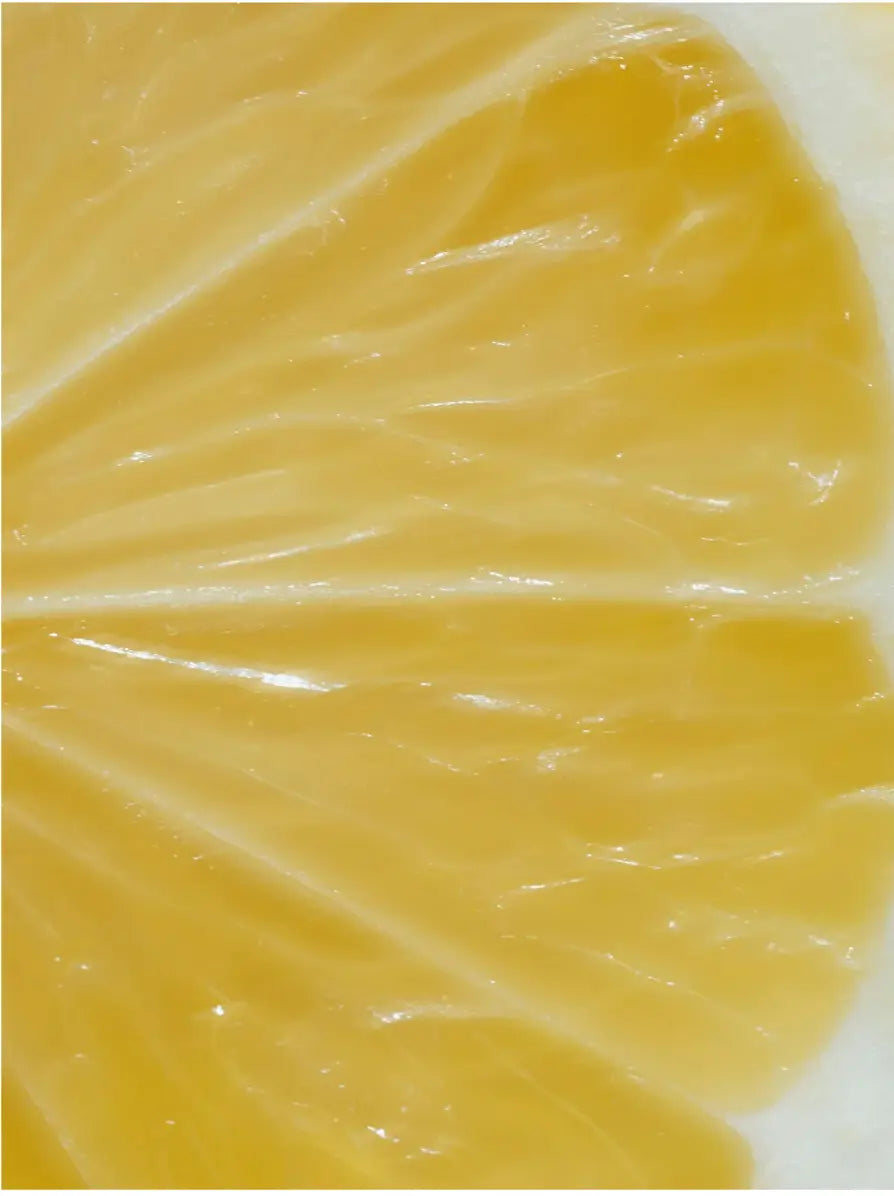 A close-up texture shot of a bright yellow citrus slice, showing the juicy segmented pulp and glossy rind.