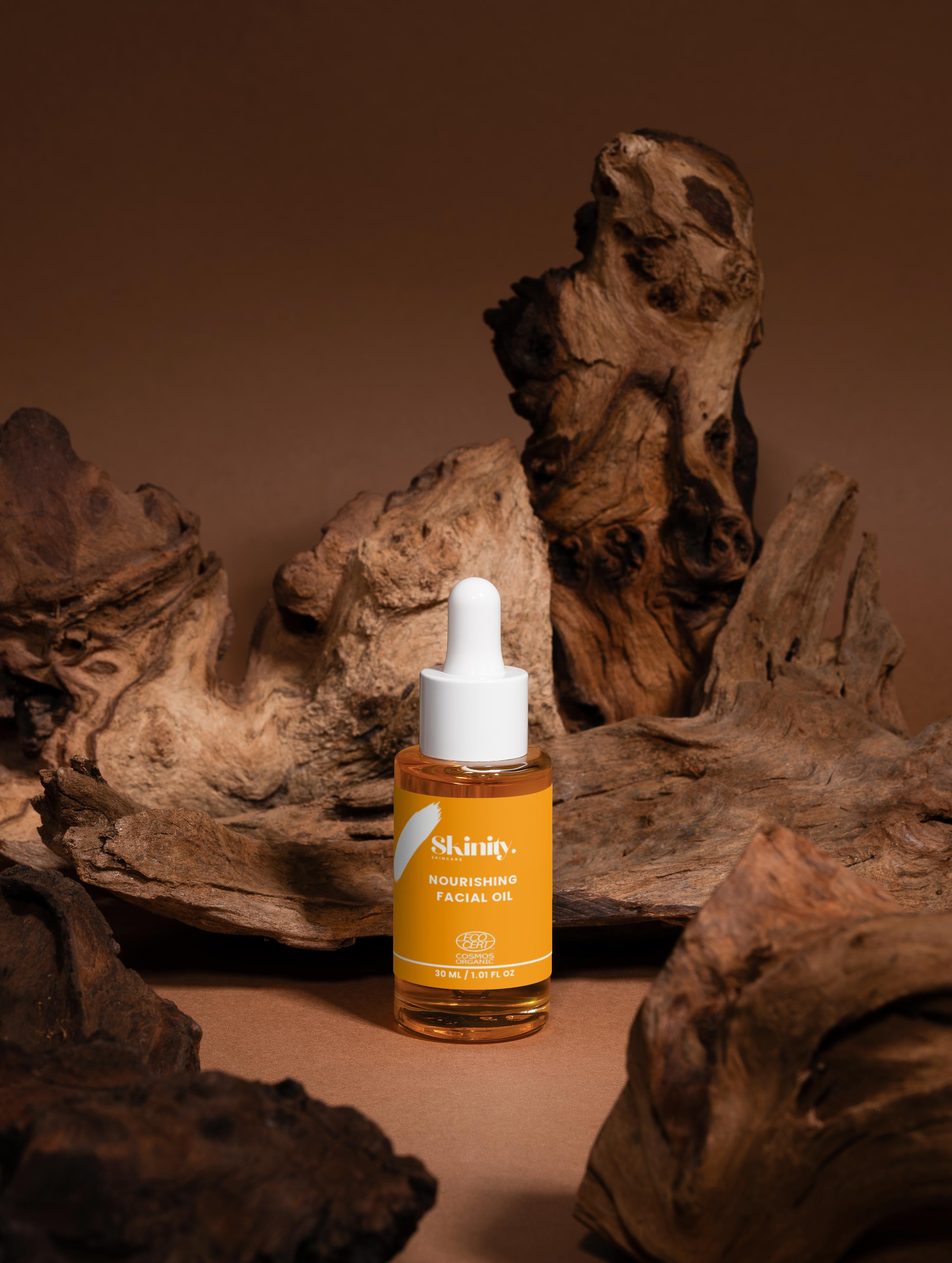 Nourishing Facial Oil For All Skin in a dropper bottle surrounded by natural wooden elements.